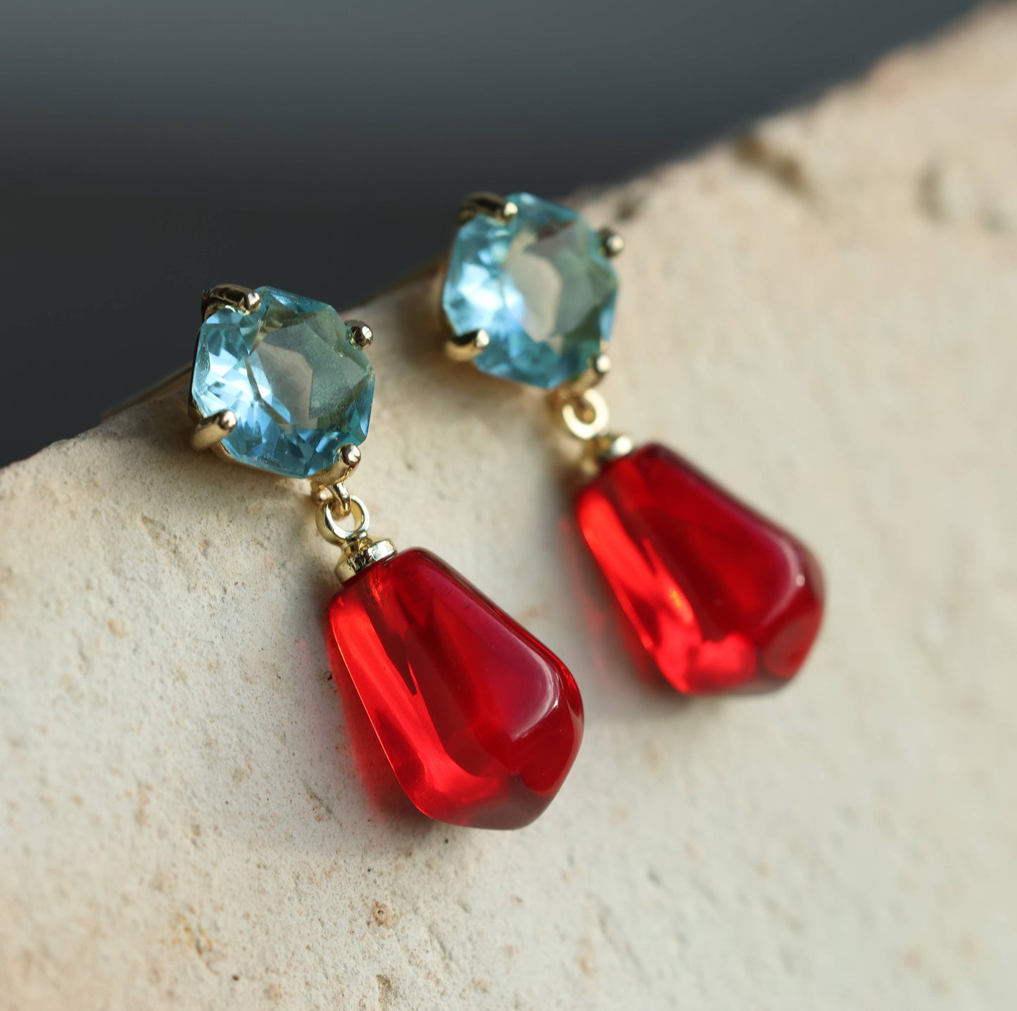 These sweet and colourful earrings feature a light sapphire blue glass jewel in a delicate, with a bright red pomegranate seed charm beneath. These earrings have a stud post fastening with butterfly backs. The blue jewels are made from glass and the pomegranate seeds are made from resin. They measure 30mm (just over one inch) in length and are light and comfortable to wear.