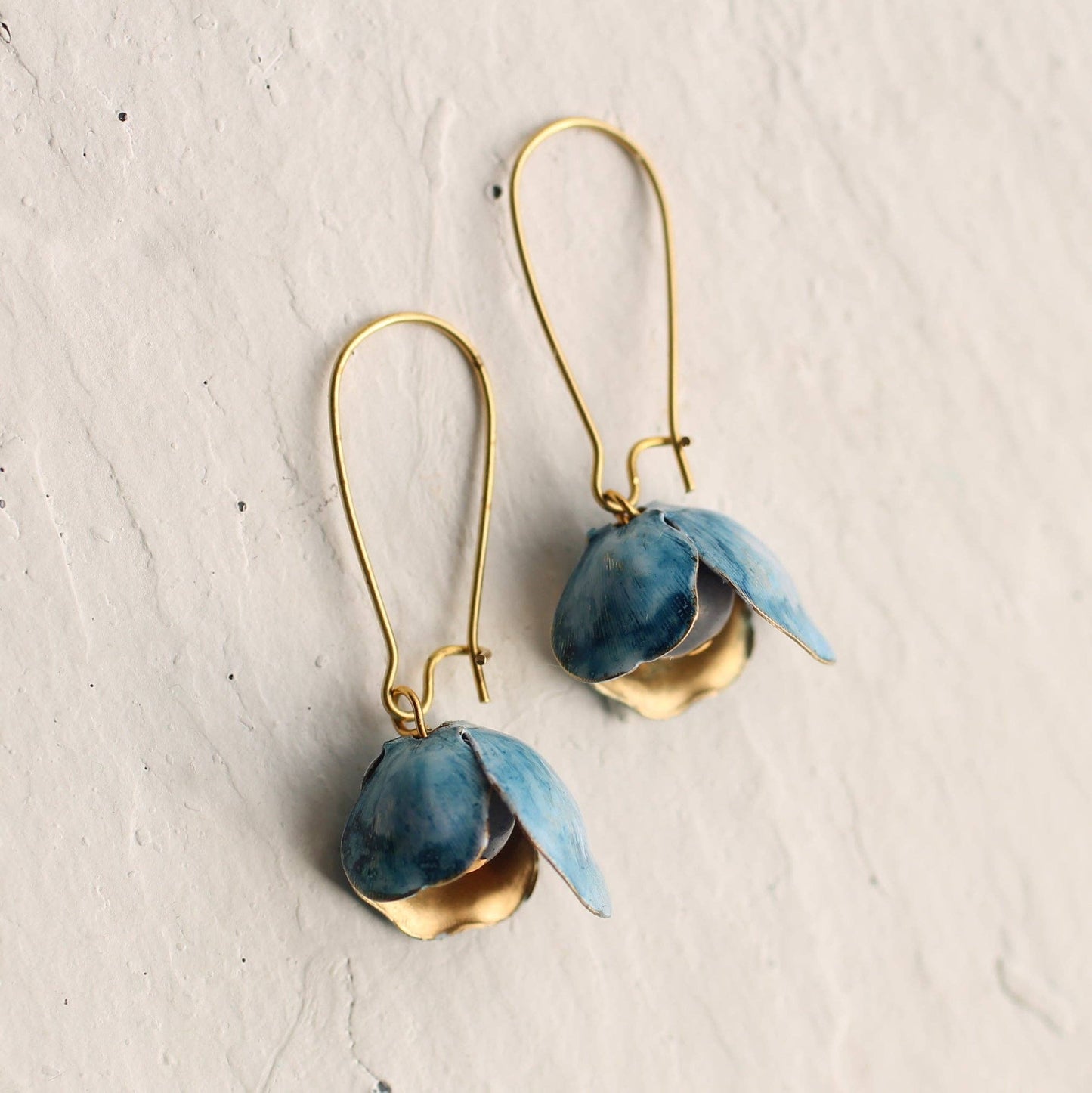 These unusual and beautiful bluebell earrings are made from vintage glass beads, layered with golden brass petals. The brass has flecks of rich blue and white paint which pick out the delicate blue of the bead underneath. The earrings are made of vintage glass and solid brass wire, and measure exactly two inches (5cm) in length.