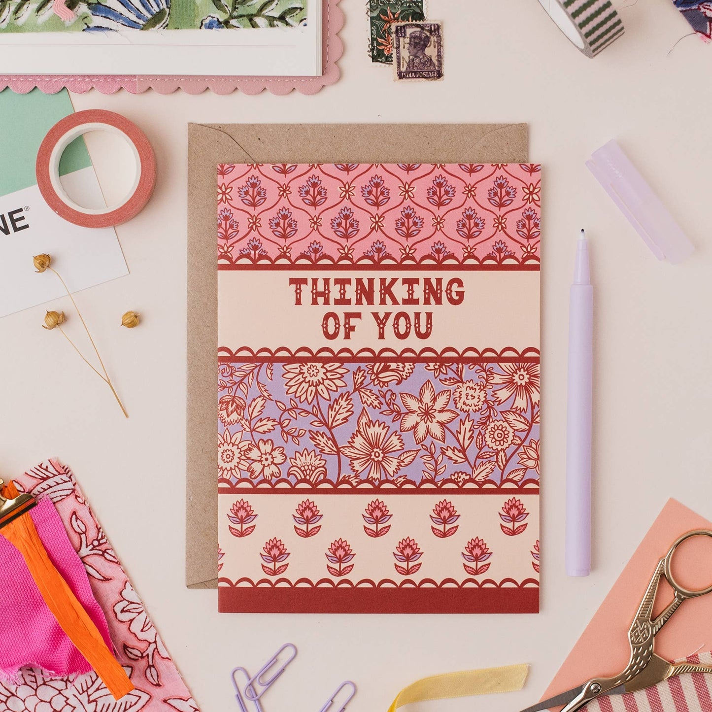 Hand drawn lettering reads 'Thinking of you'. Illustrated greeting card with Indian block print inspired floral pattern, printed onto premium matt card with a kraft envelope.