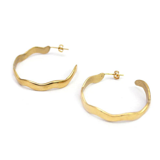 Close-up of Kilifi wavy recycled brass hoop earrings, ethically handmade in Kenya, showcasing the unique texture and gold finish.