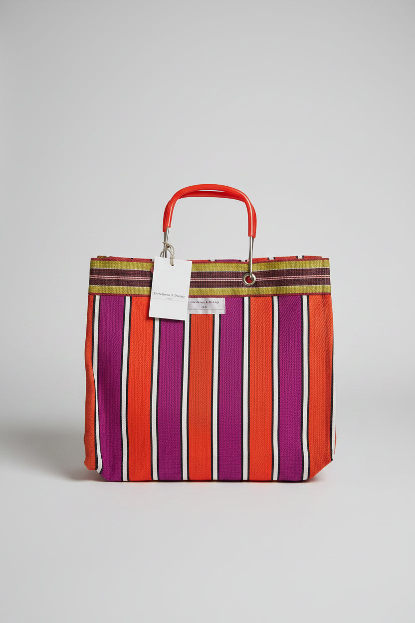 A striped tote bag with alternating orange, purple, and white vertical stripes with a metal handle