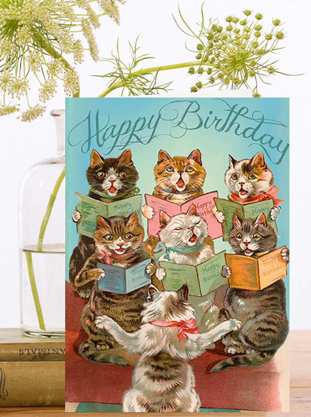 Close-up of vintage-style birthday card showing a choir of anthropomorphic cats singing 'Happy Birthday' with sheet music, designed by Madame Treacle.