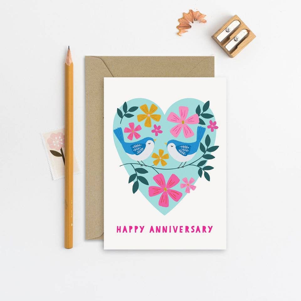 Featuring original artwork of two adorable little birds on a branch in front of a flower-filled heart, this adorable anniversary card is a gender neutral design perfect for couples of all kinds. With the words Happy Anniversary .