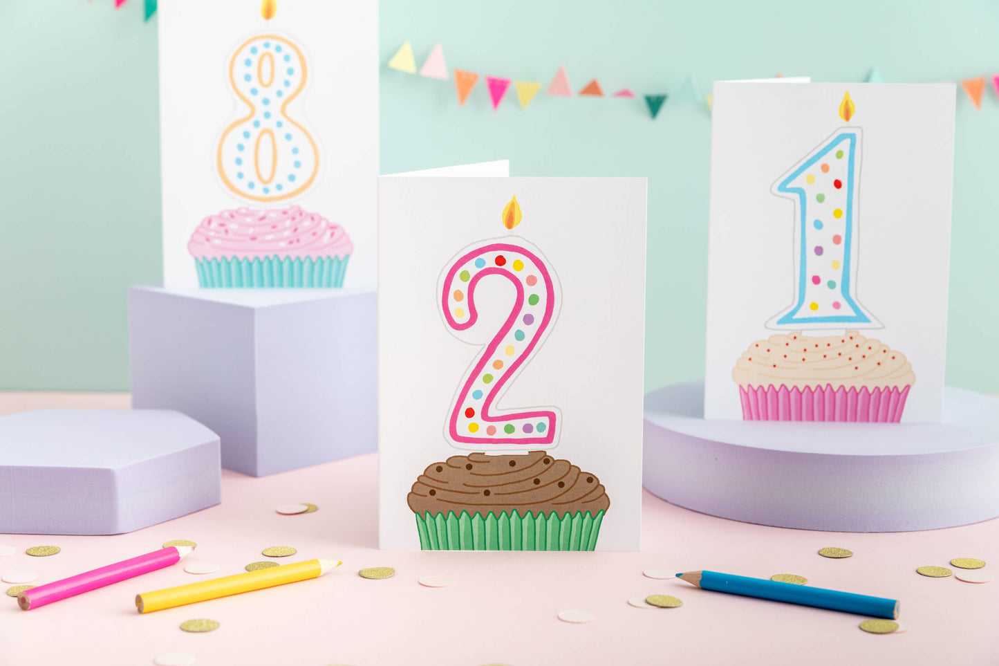 Brightly coloured cupcake 2nd birthday card with a number two candle, supplied with a Kraft envelope, on a white background.