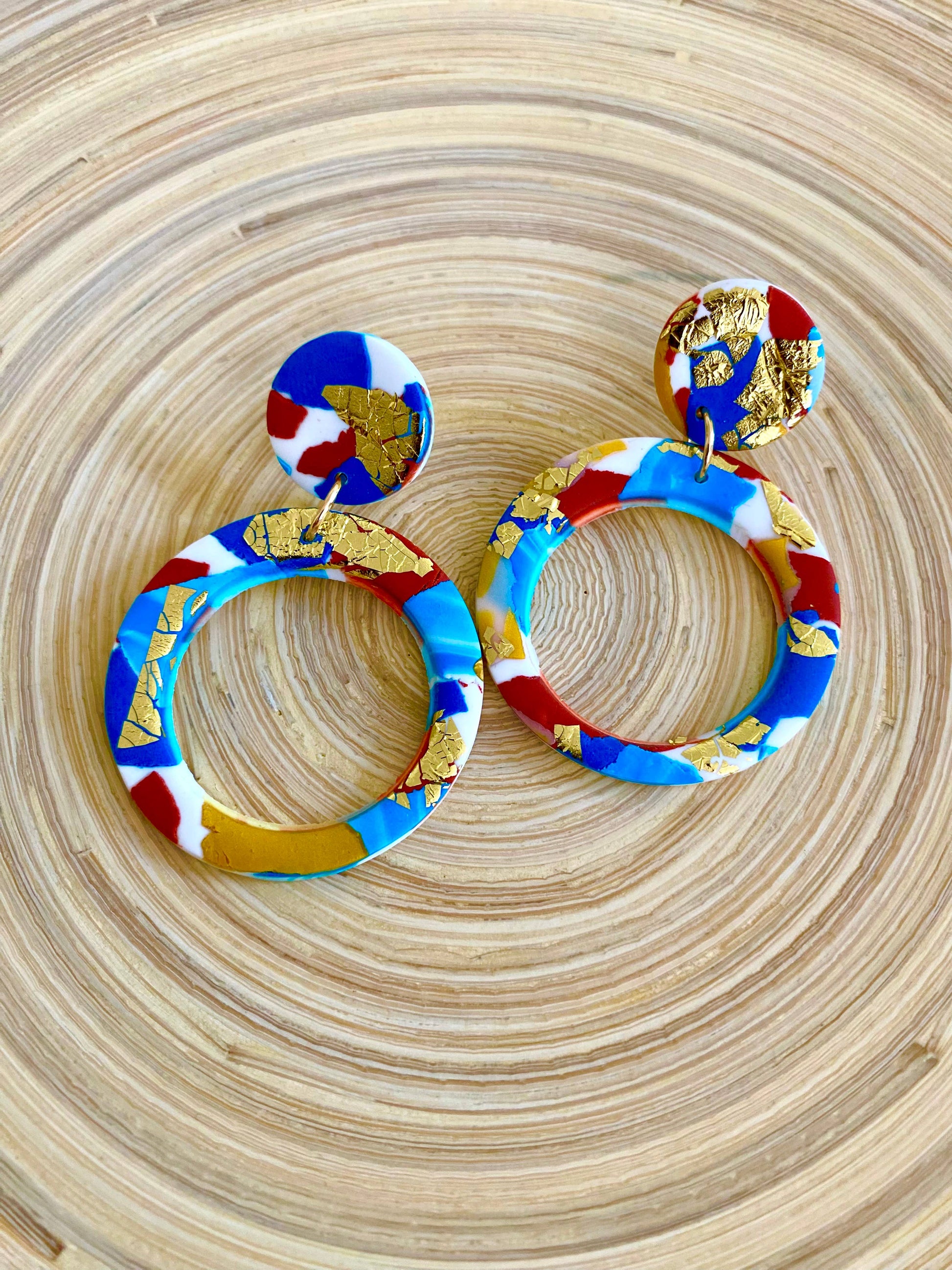Large polymer clay hoop earrings with turquoise, teal, white and terracotta colours, and splashes of gold leaf.