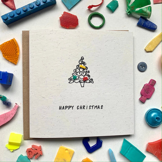 White card with a Christmas tree design and 'Happy Christmas' text, surrounded by colorful building blocks.
