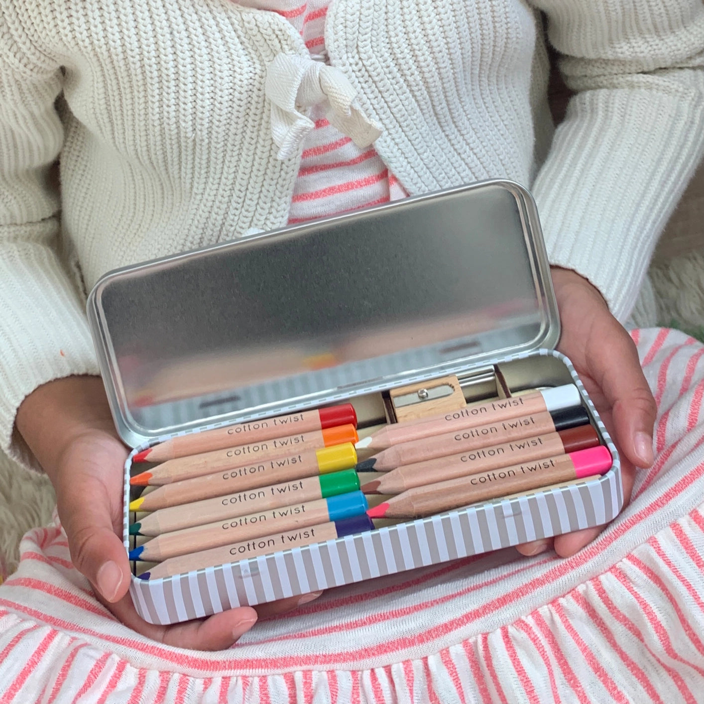 Person holding vibrant Cotton Twist jumbo watercolour pencils in a tin.