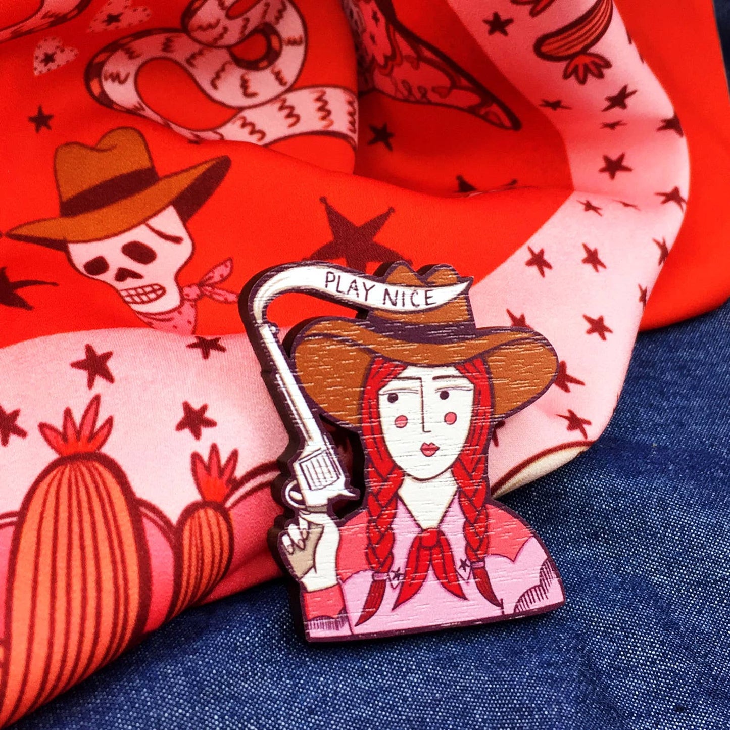 Cowgirl wooden pin brooch with 'Play Nice' message, original illustration by Su Owen, made from sustainable walnut wood, secure metal bar back, UK-made.