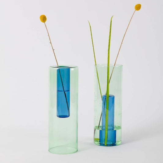 Two Block Design reversible glass vases in blue and green on a clean white background.