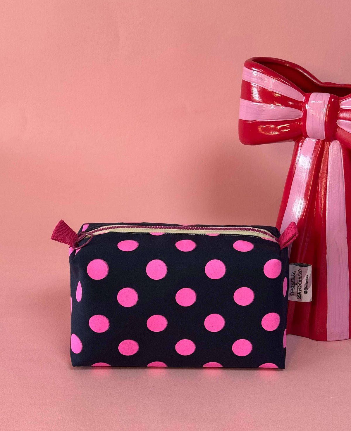 Side view of pink and navy polka dot travel bag
