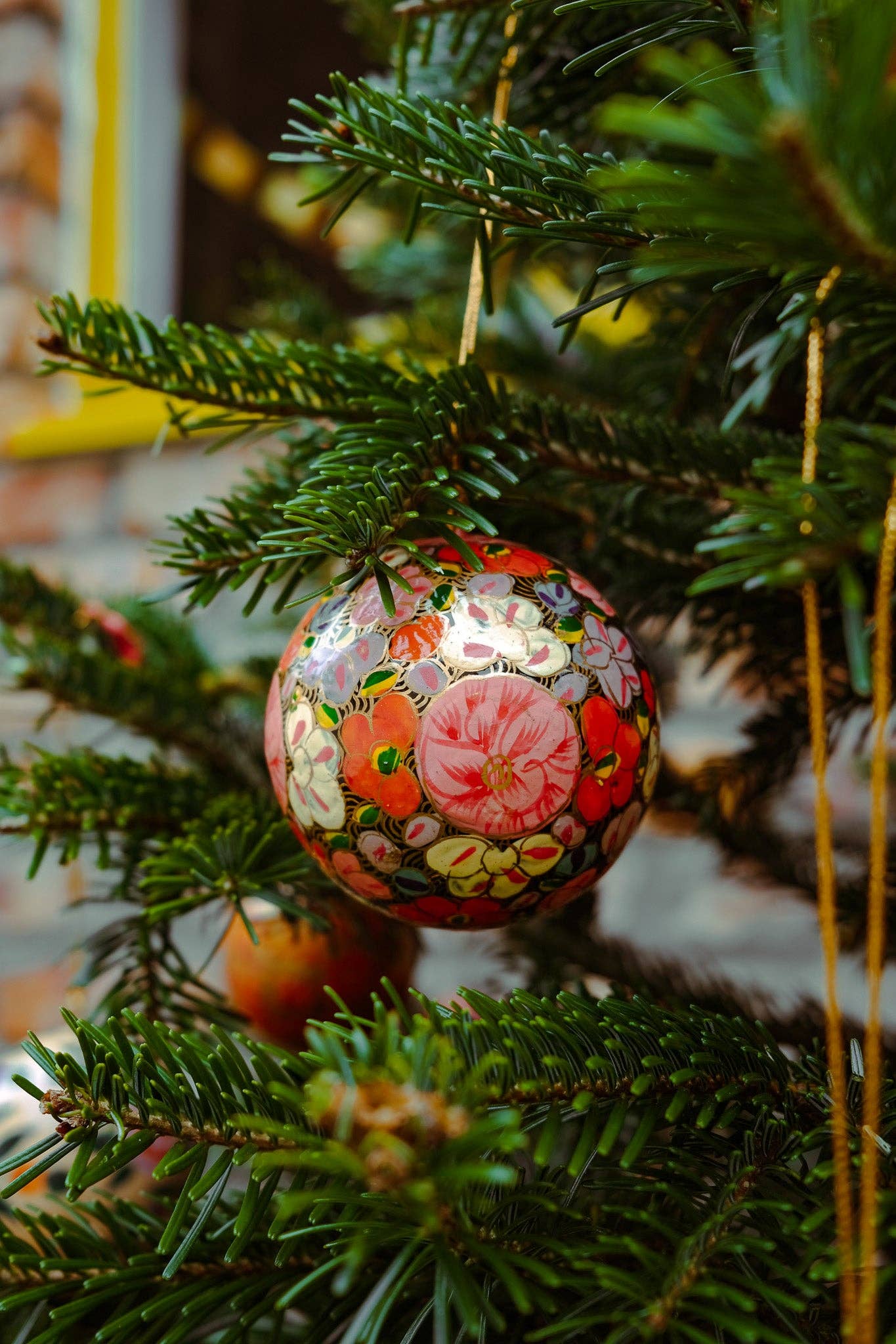 Close-up of a single Gold Floret Papier Mâché Christmas Bauble, showing intricate hand-painted design.