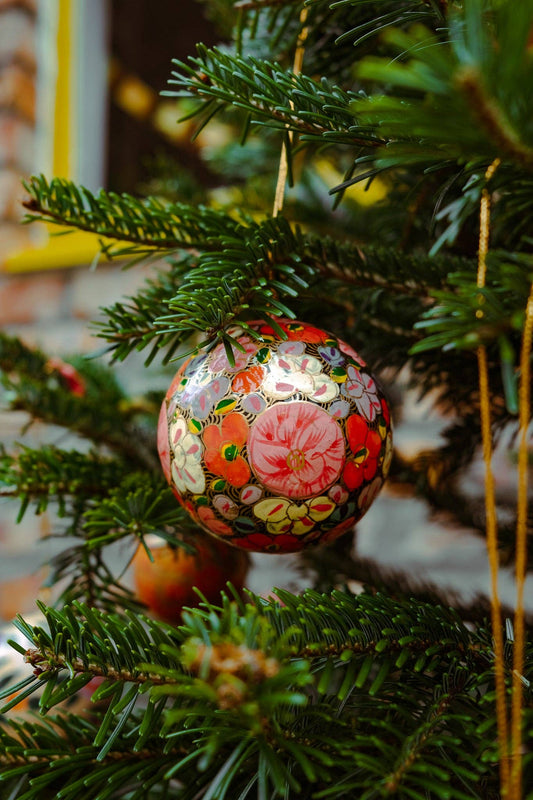 Close-up of a single Gold Floret Papier Mâché Christmas Bauble, showing intricate hand-painted design.