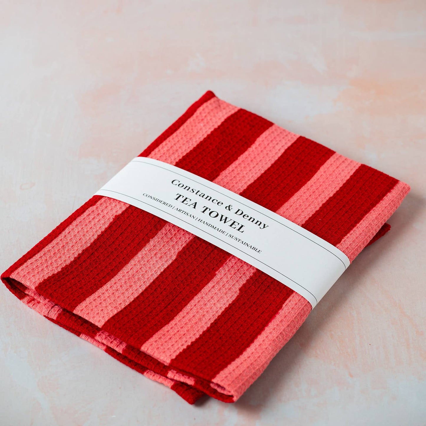 Crimson wide stripe waffle cotton tea towel hanging on a hook