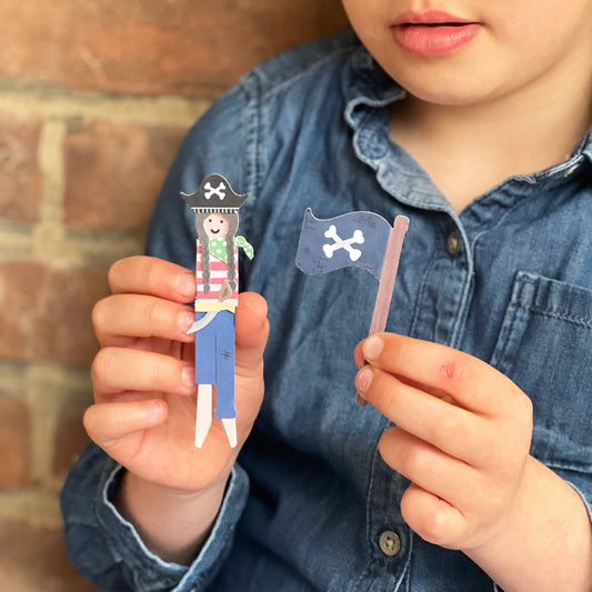 Child's hands crafting a pirate peg doll with included accessories