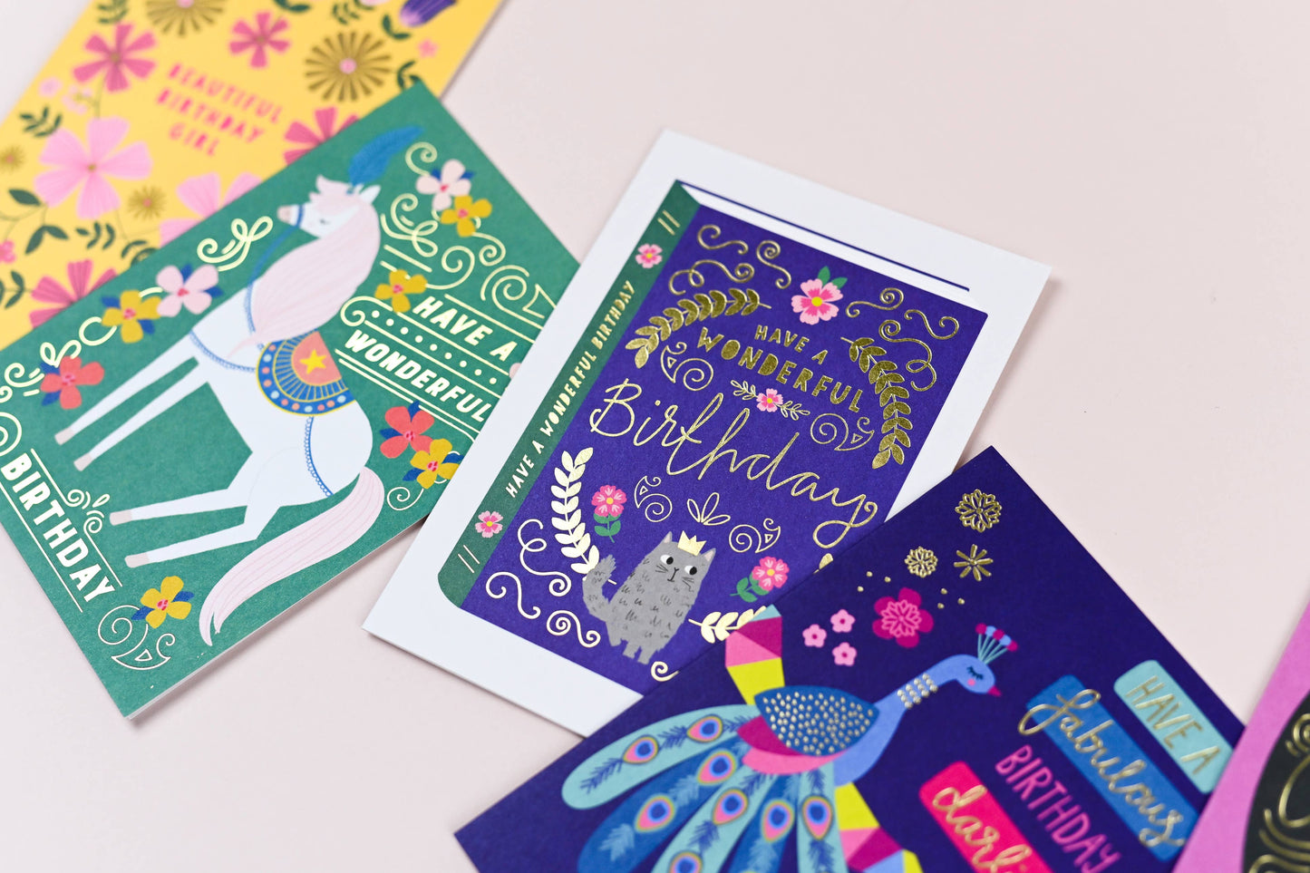 Colorful birthday cards with various designs on a light pink background