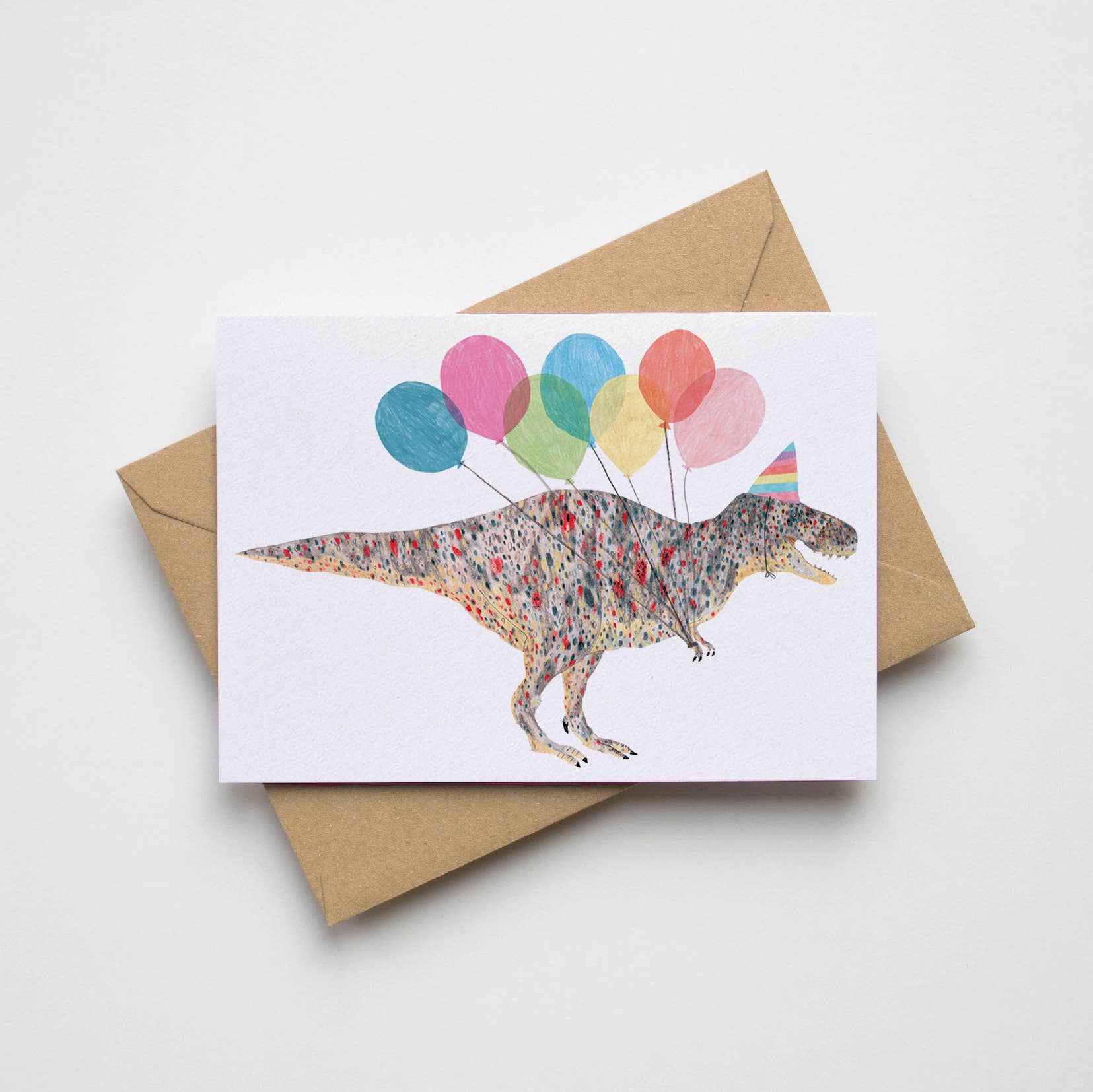 Playful T-Rex dinosaur birthday card with party balloons and a kraft envelope