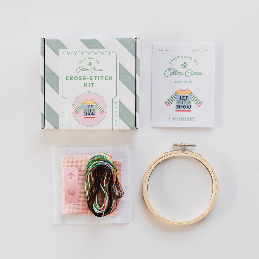 Contents of the beginner Christmas cross stitch kit including pink Aida and threads