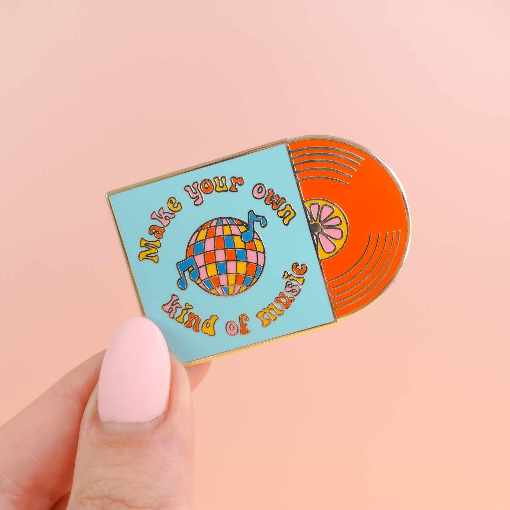 Colorful vinyl record-shaped pin with 'Make your own kind of music' text on a pink background