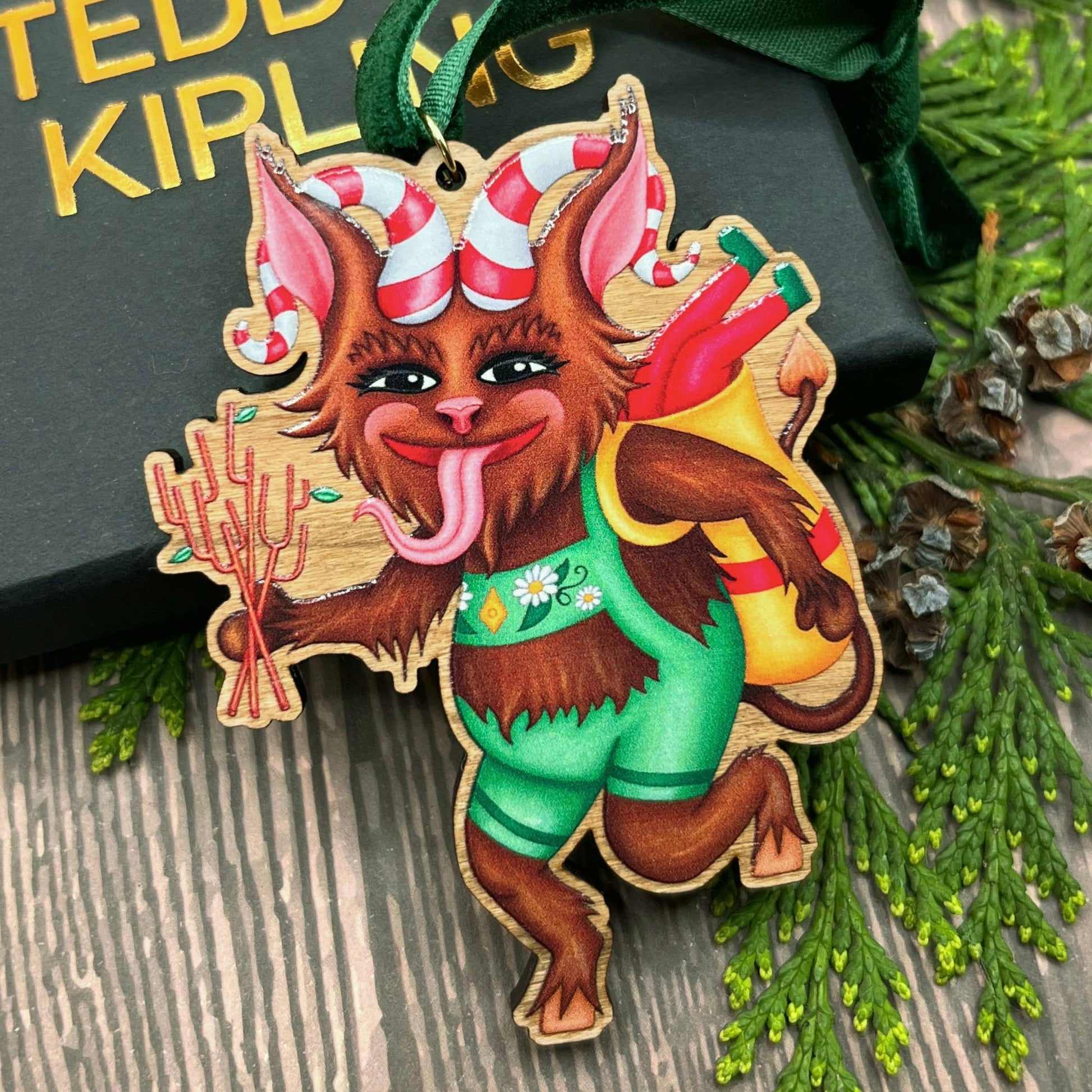 Krampus wooden Christmas tree decoration featuring Teddy & Kipling illustration, sustainably certified cherry wood, gold-plated ring, and dark green velvet ribbon