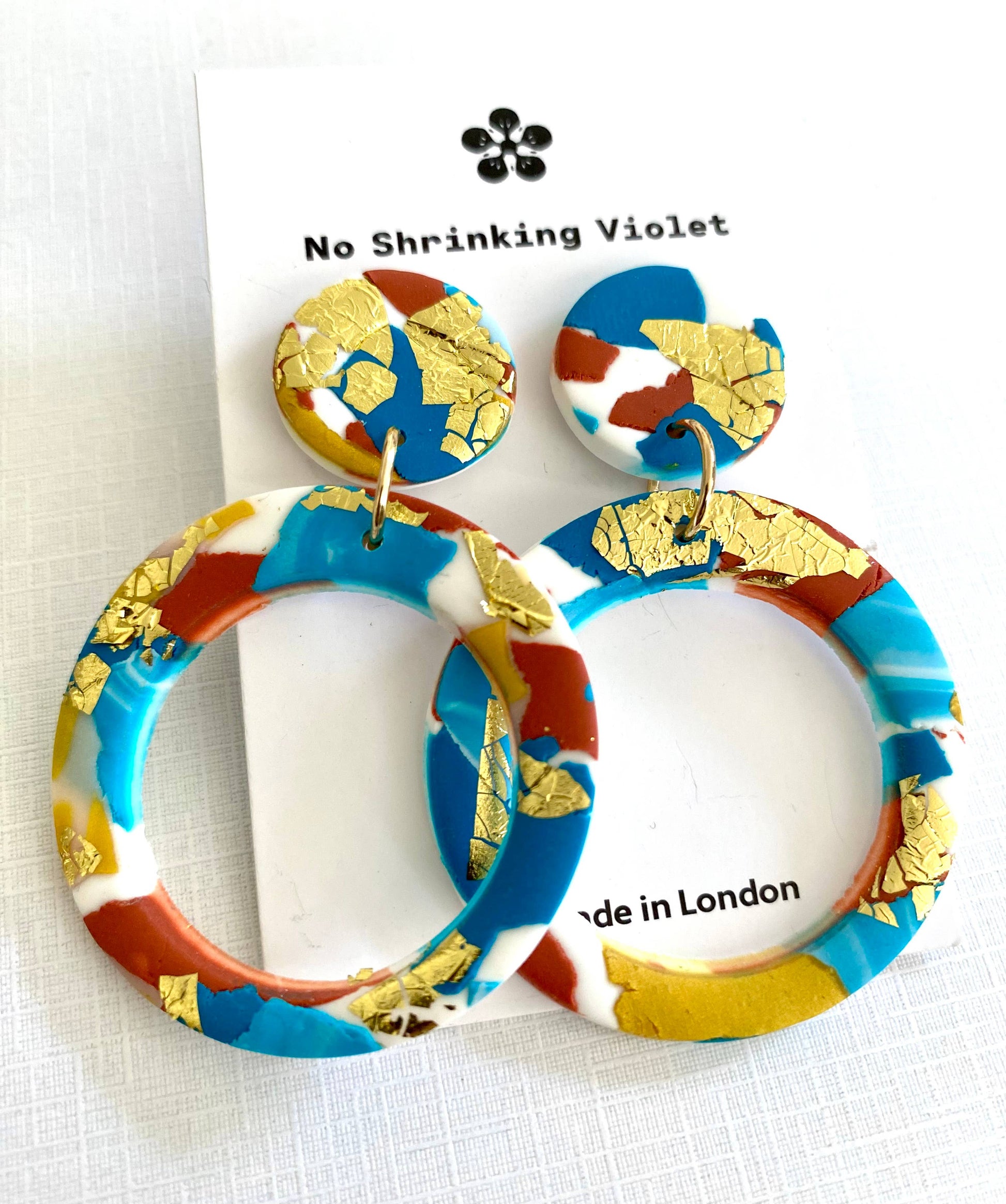 Large polymer clay hoop earrings with turquoise, teal, white and terracotta colours, and splashes of gold leaf.