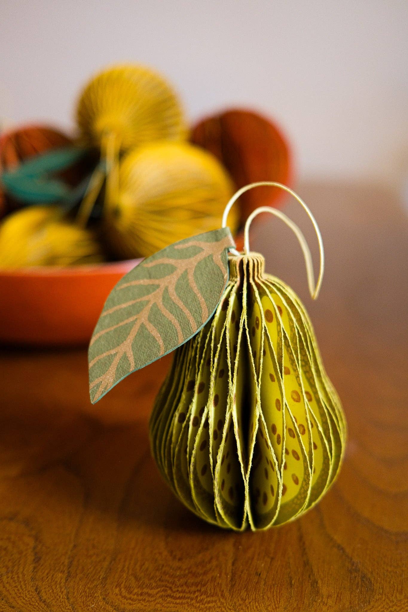 Hand holding a recycled paper pear honeycomb ornament, showing scale