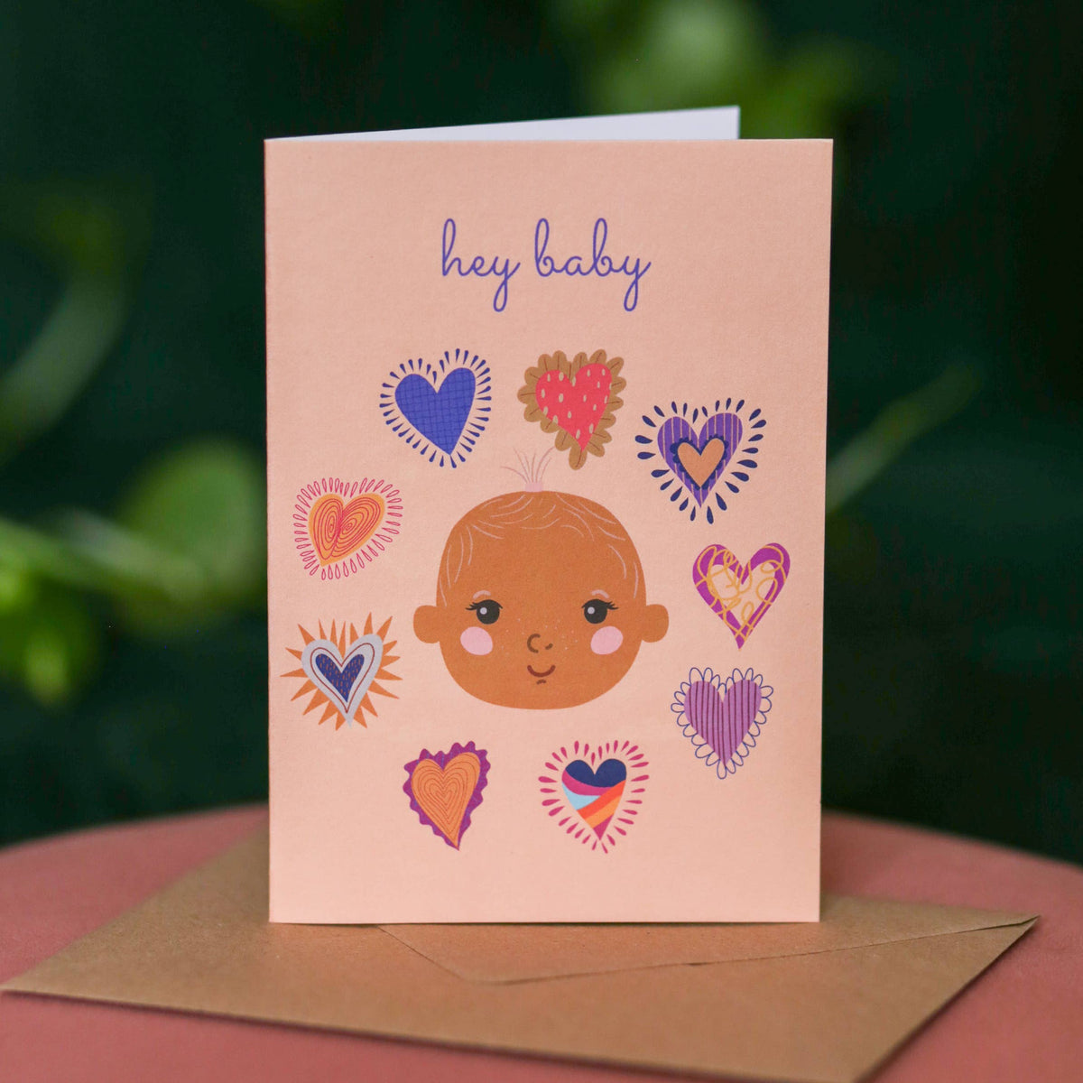 Inclusive new baby card featuring a diverse baby and hearts design
