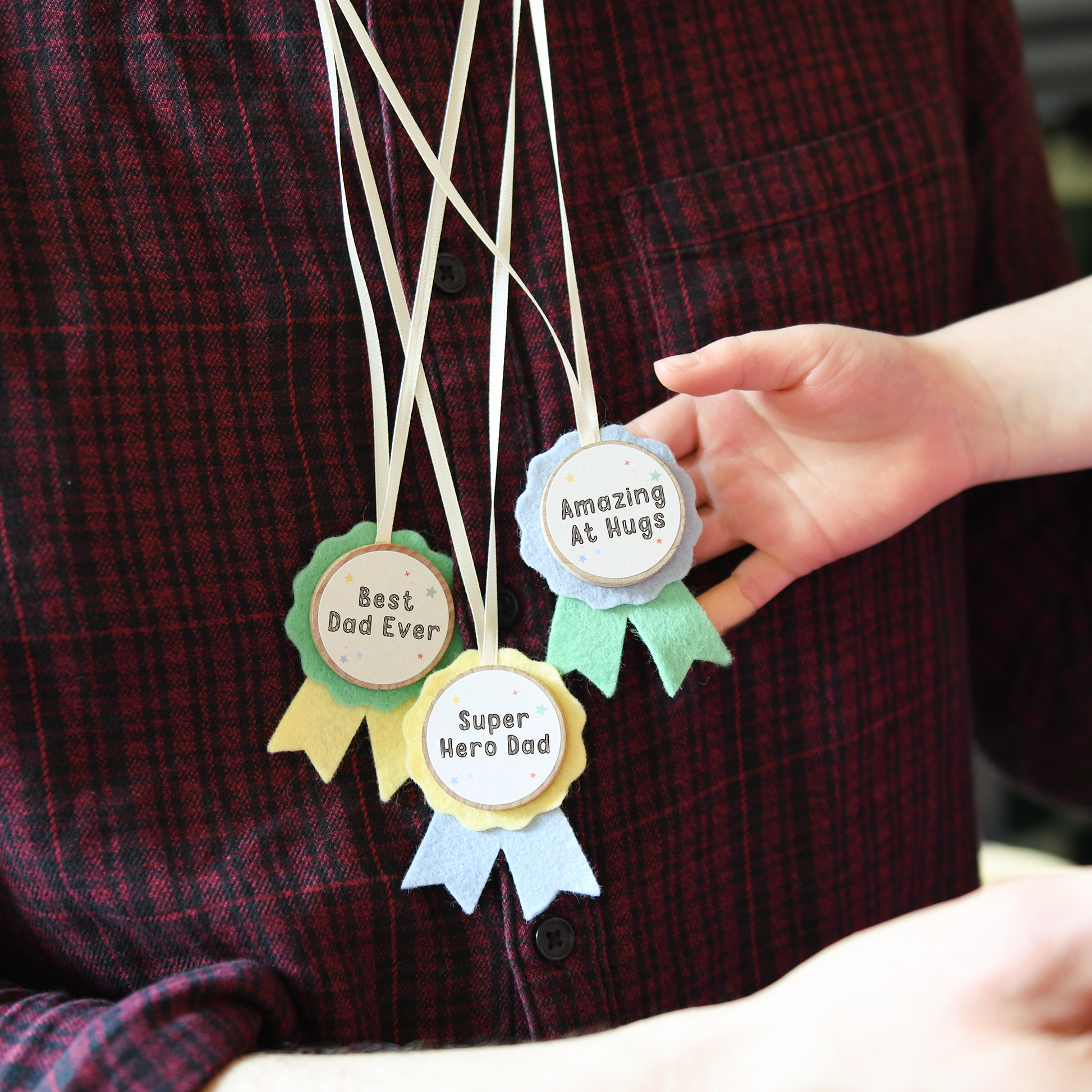 A dad wearing the handmade medals Best Dad Ever, Super Hero Dad and Amazing at Hugs