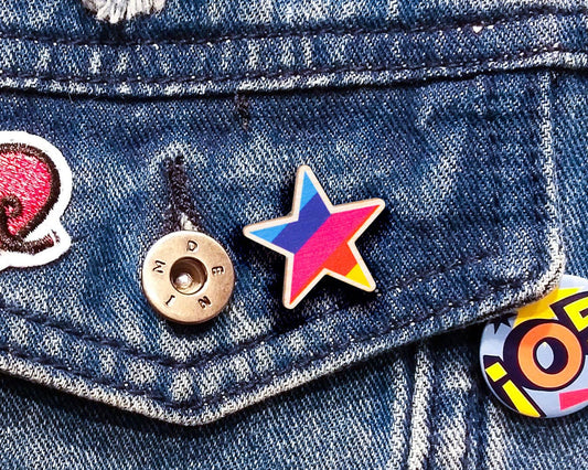 Rainbow Star Pin Badge displayed on a denim jacket, showcasing its size and bright colours