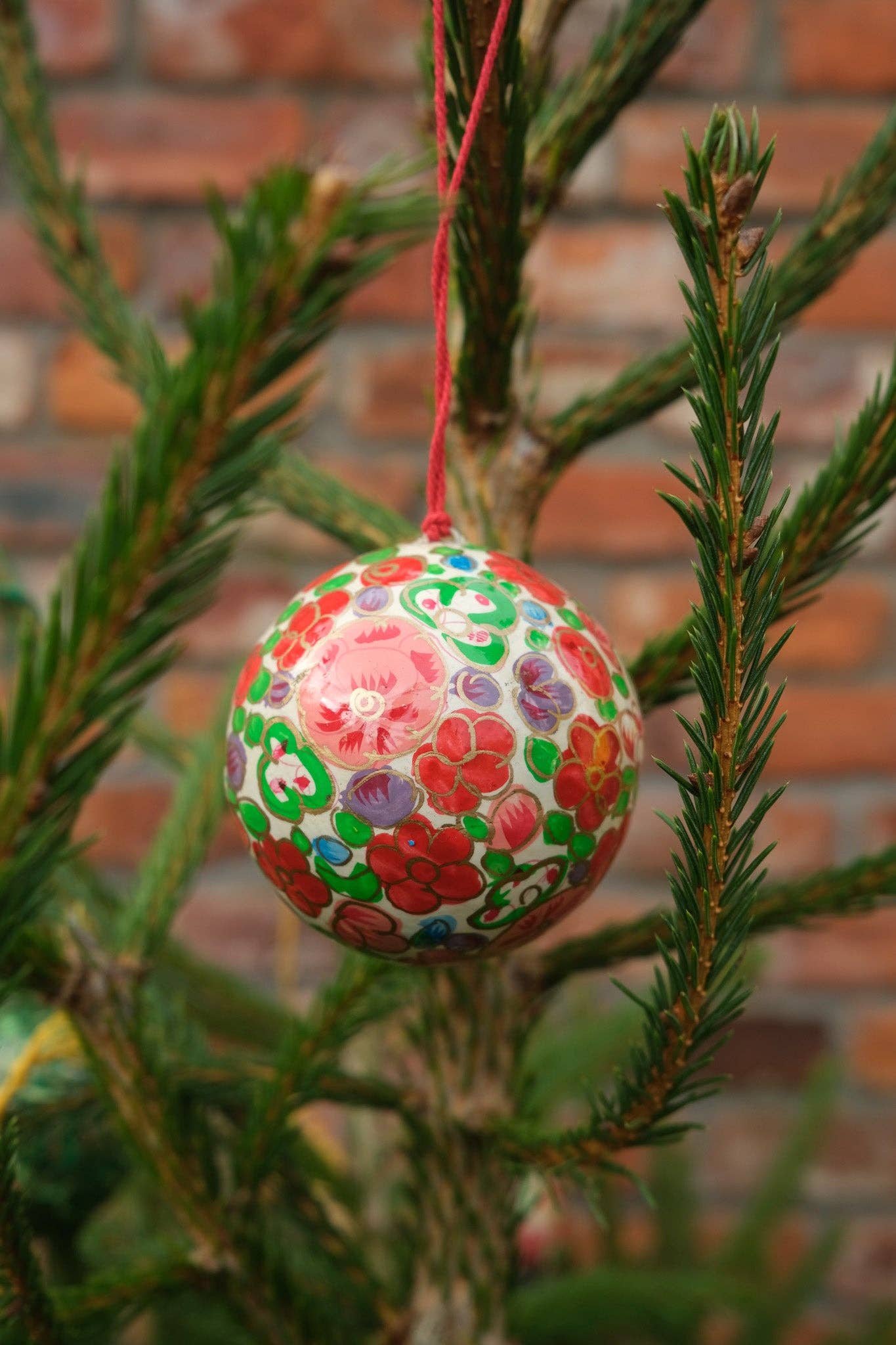 Intricate hand-painted crimson flower pattern on recycled bauble