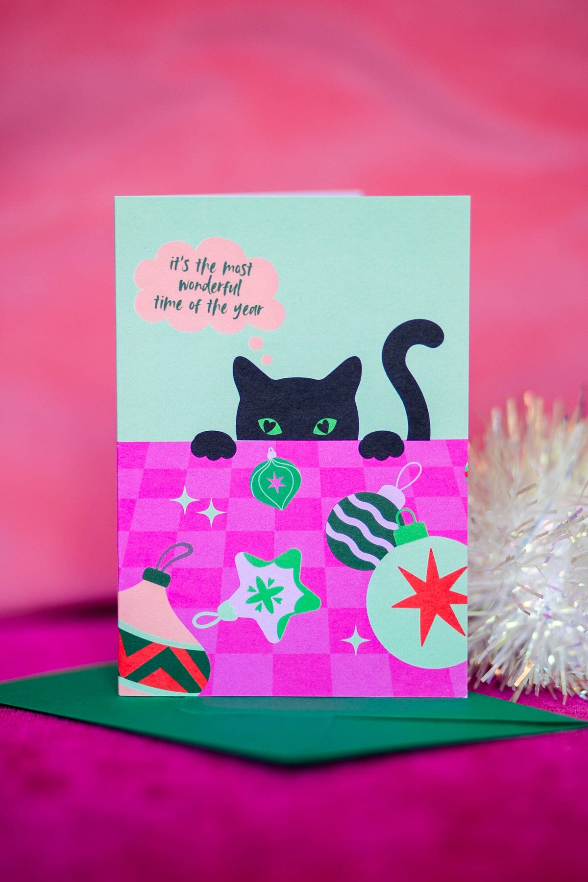 Funny black cat eyeing Christmas baubles illustration on A6 card