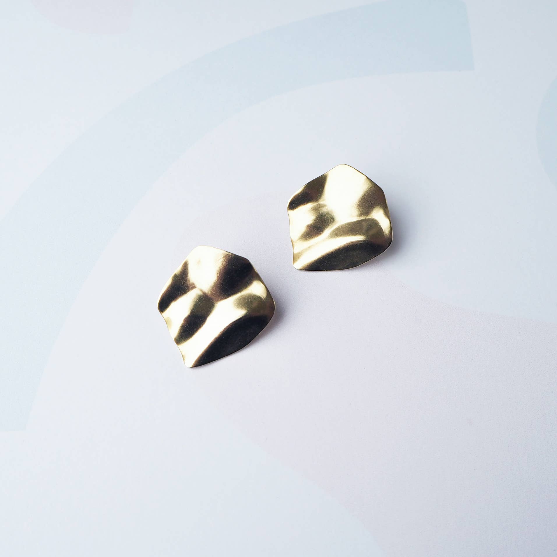 Purl wavy gold stud earrings on branded display card