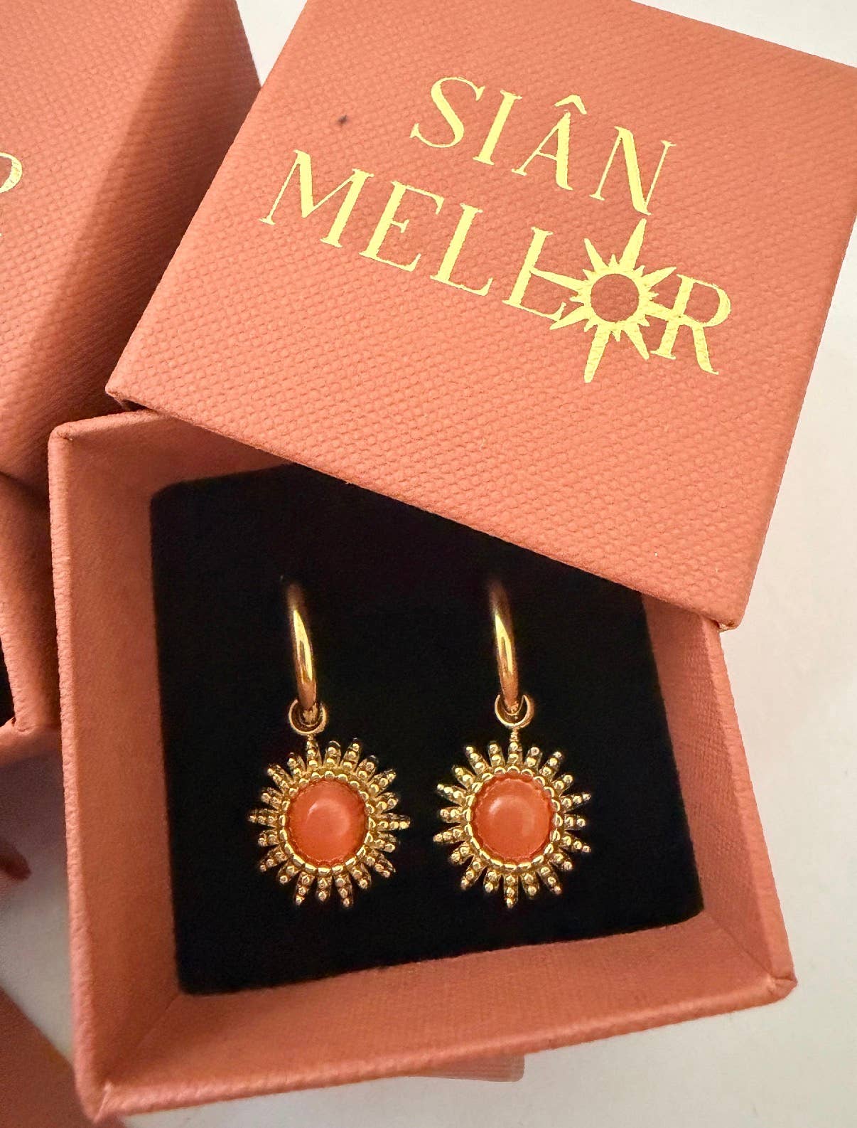 Close up of pink 18k gold plated sun hoop earrings