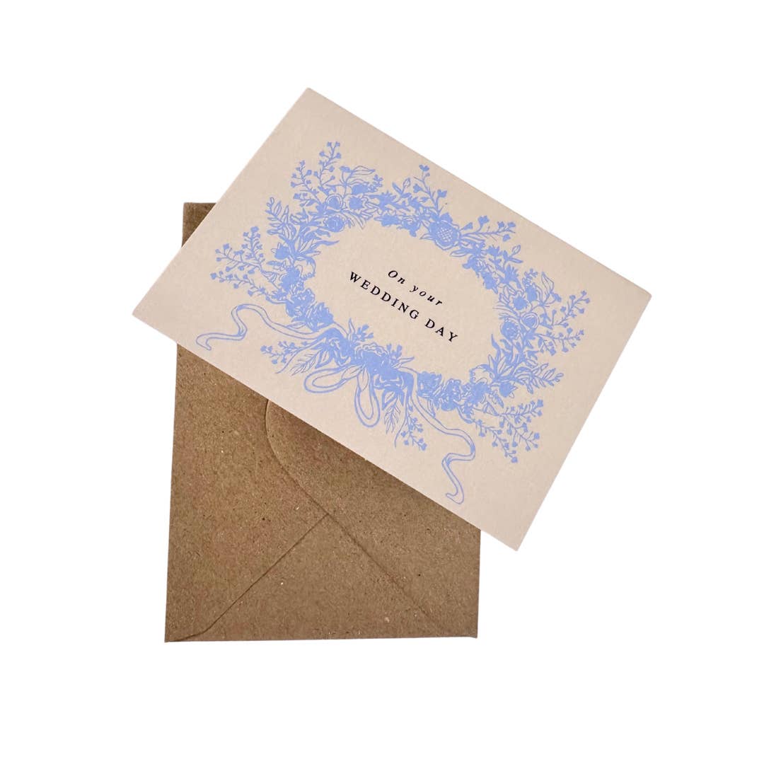 Wedding card with blue floral design and 'On Your Wedding Day' text, paired with a brown envelope on a white background.