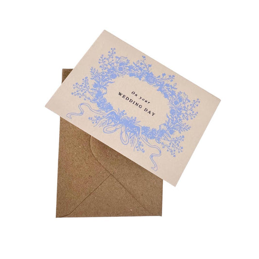 Wedding card with blue floral design and 'On Your Wedding Day' text, paired with a brown envelope on a white background.