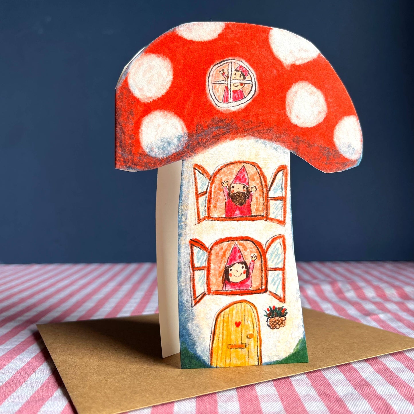 Whimsical red and white toadstool house greeting card, featuring elves waving from windows. Perfect for new home celebrations.