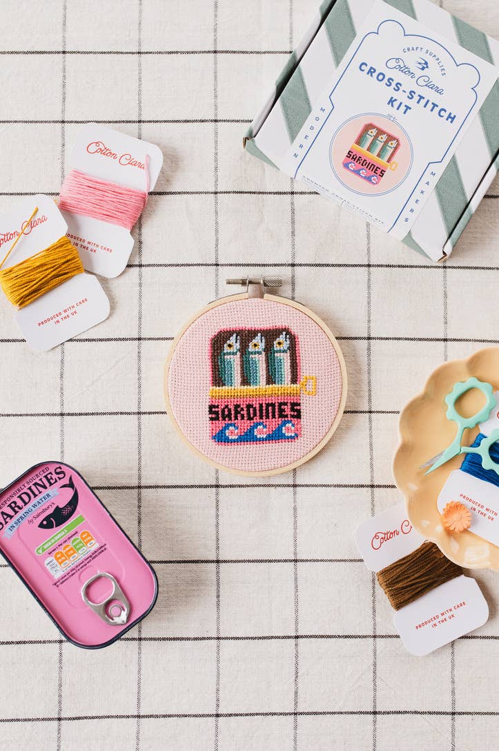 Sardines Cross Stitch Kit for beginners, featuring a 4-inch wooden hoop, coloured Aida fabric, embroidery thread, and eco-conscious packaging. Made in UK.
