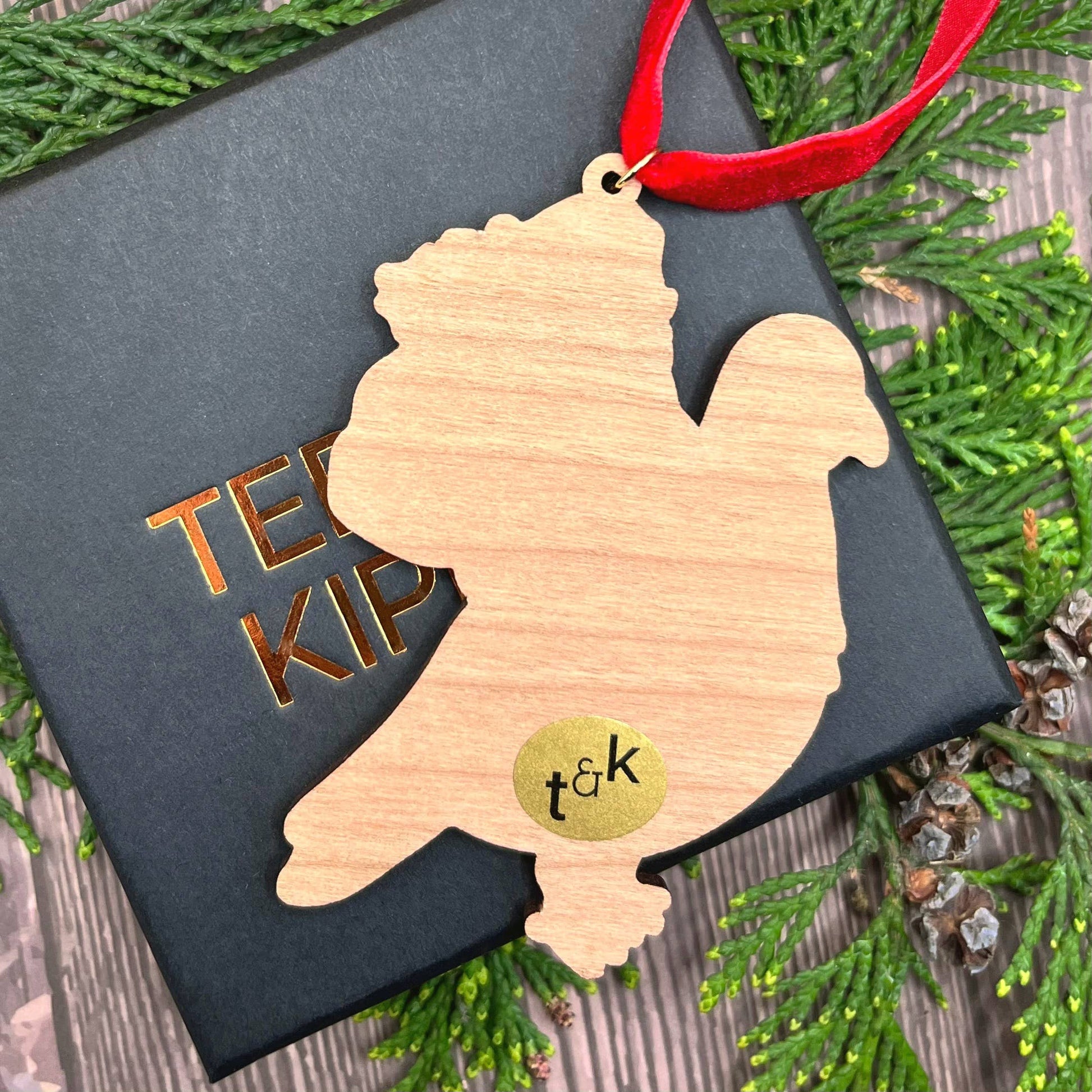 Santa Pigeon wooden Christmas tree decoration with Teddy & Kipling illustration, sustainably certified cherry wood, gold-plated ring, and red velvet ribbon.