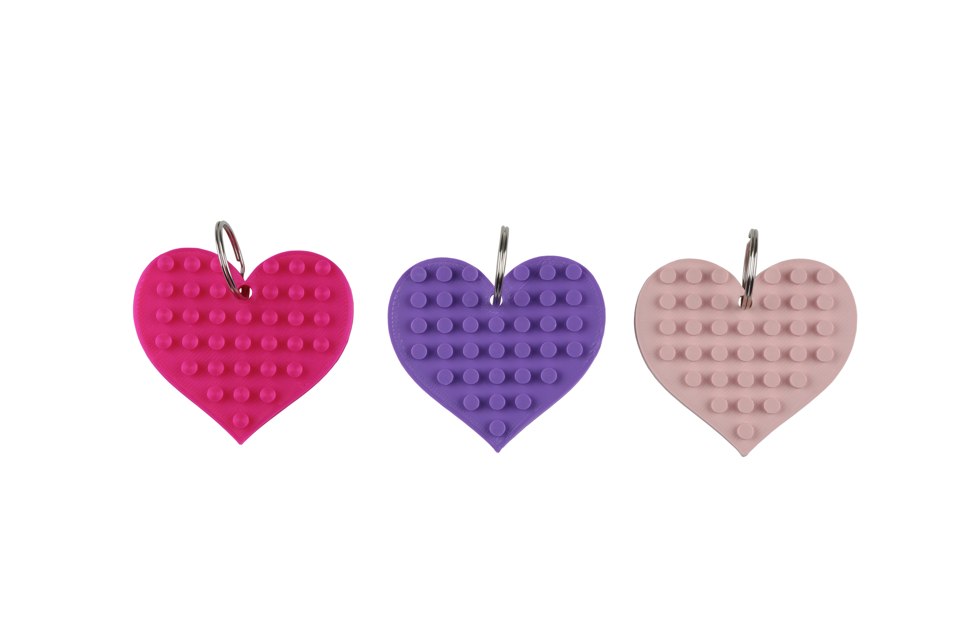 Three heart-shaped keychains in pink, purple, and pink on a white background