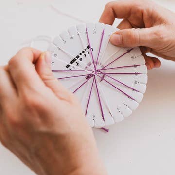 Person using the Kumihimo loom to braid a bracelet