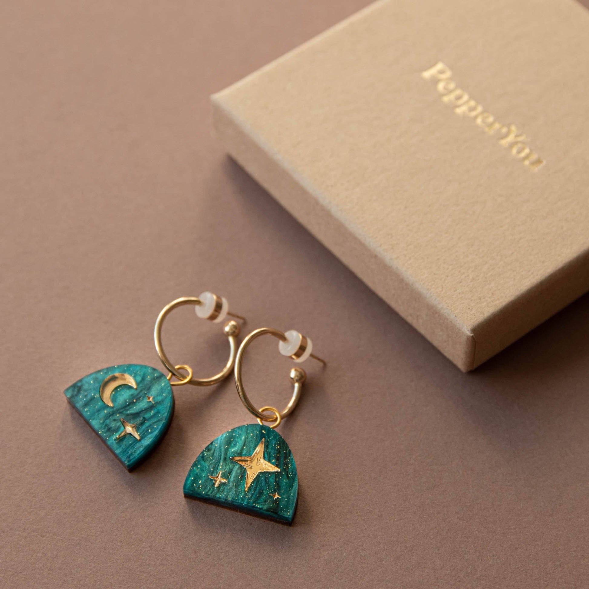 Pair of Teal Marble & Gold Moon Rising Arc Hoop Earrings on a recycled paper card, highlighting the sustainably sourced wood.