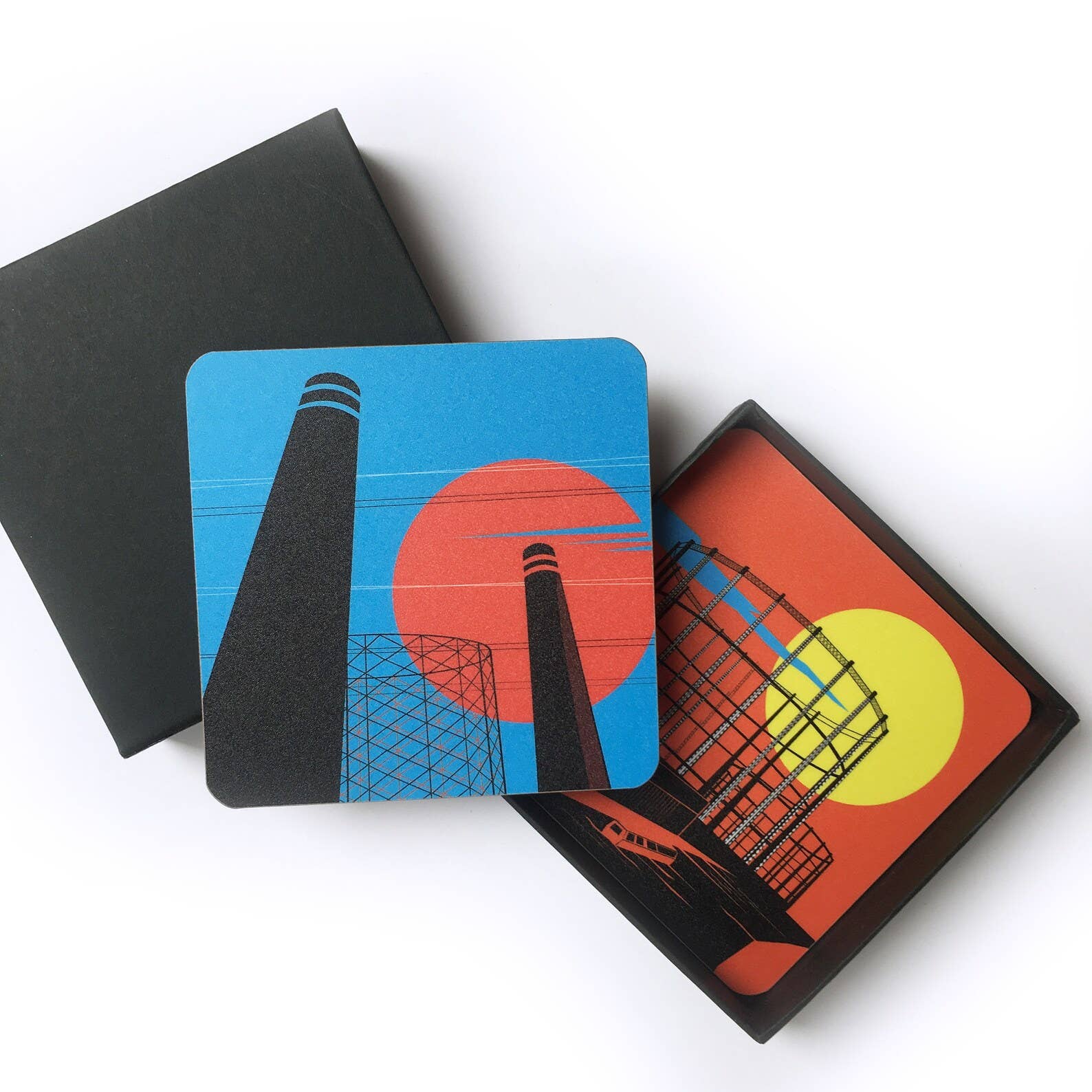 Industrial London Coaster Gift Set. Set of 4 coasters featuring London Landmarks. Battersea, Hackney, Croydon and Brick Lane Gasholders and chimneys. The gritty, not so pretty side of industrial London. Featuring the Battersea Power station, the gasworks at Waddon Marsh Croydon, the chimney of the Old Truman Brewery, and the gas holders by the canal in Hackney, as seen from an overground train. The coasters come in a smart black box, with the words Industrial London Coaster Set in white font.