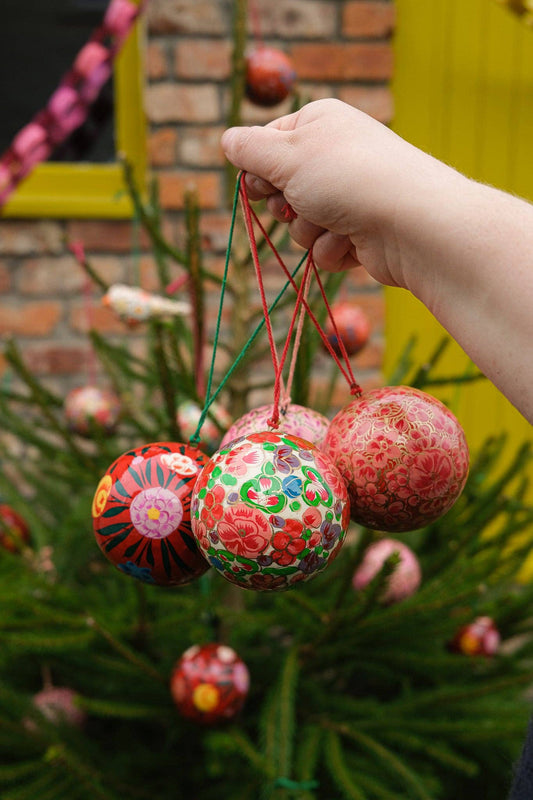 Detailed close-up of hand-painted crimson flower design on bauble