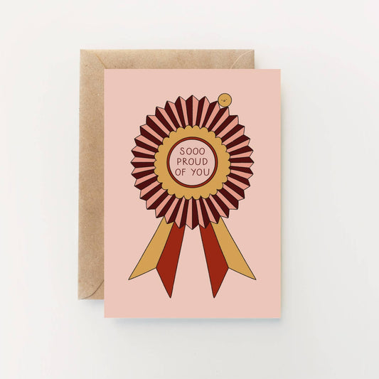 Greeting card with a ribbon design and 'SOOO PROUD OF YOU' text on a pink background. Illustrated “Sooo Proud of You” greetings card by Hollie Fuller, eco‑friendly UK‑made design