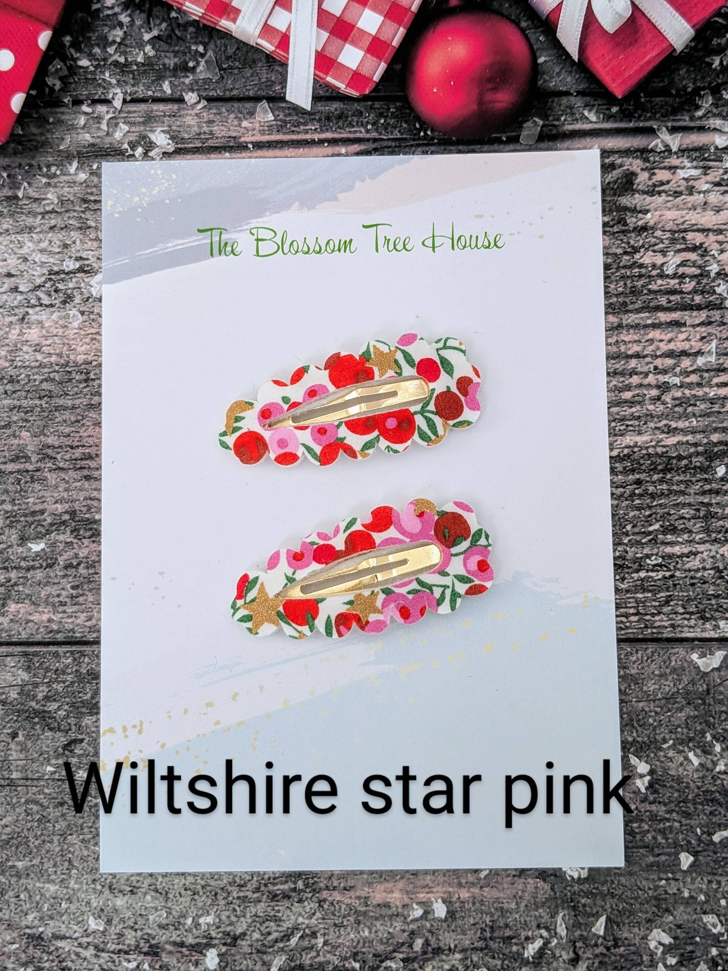 Two floral hair clips on a card with 'The Blossom Tree House' branding, set against a rustic wooden background.