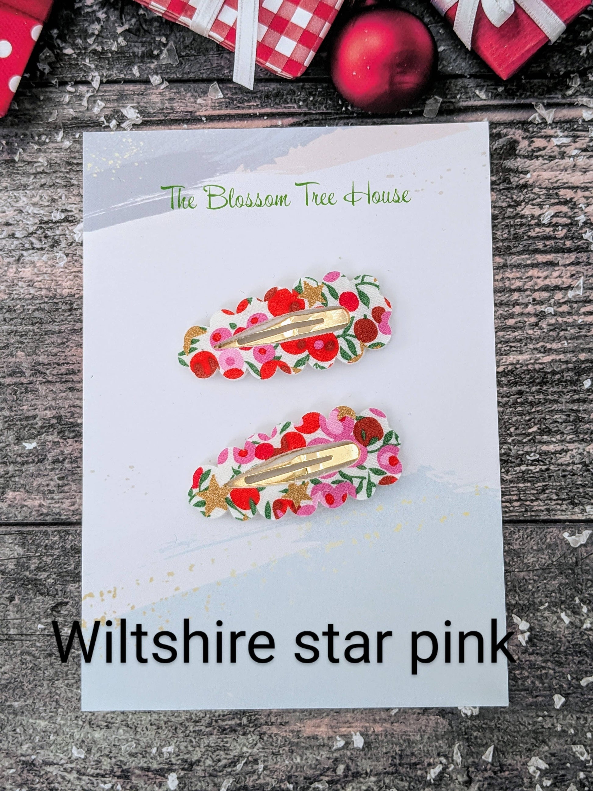 Two floral hair clips on a card with 'The Blossom Tree House' branding, set against a rustic wooden background.