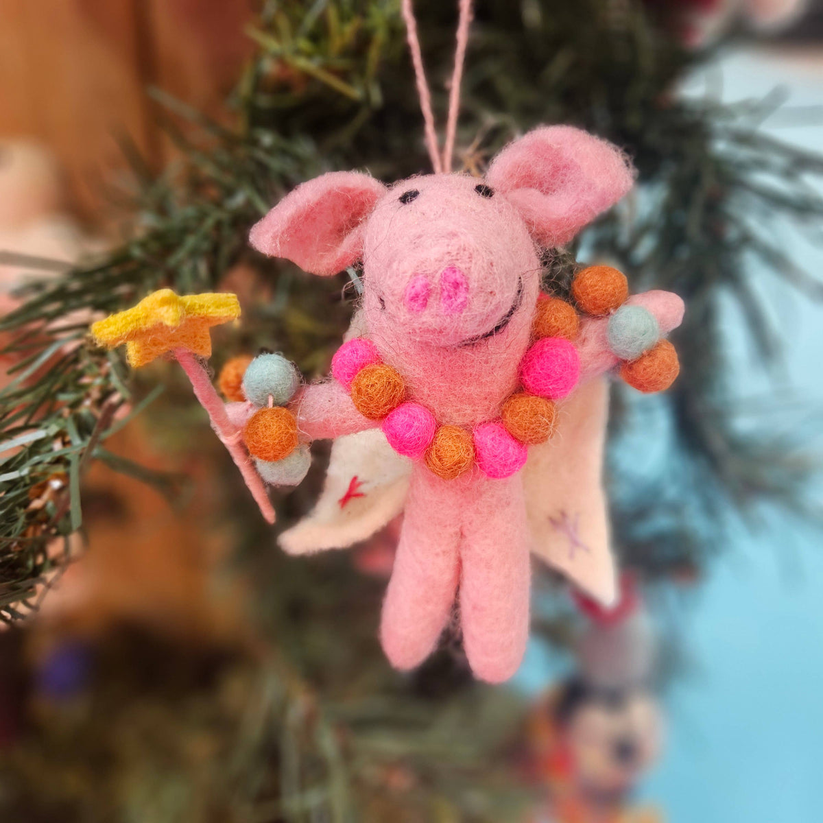 Felt Penelope Porker pig fairy ornament hanging on Christmas tree branch