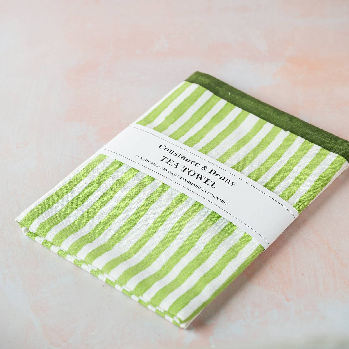 Green stripe cotton tea towel hanging in a kitchen