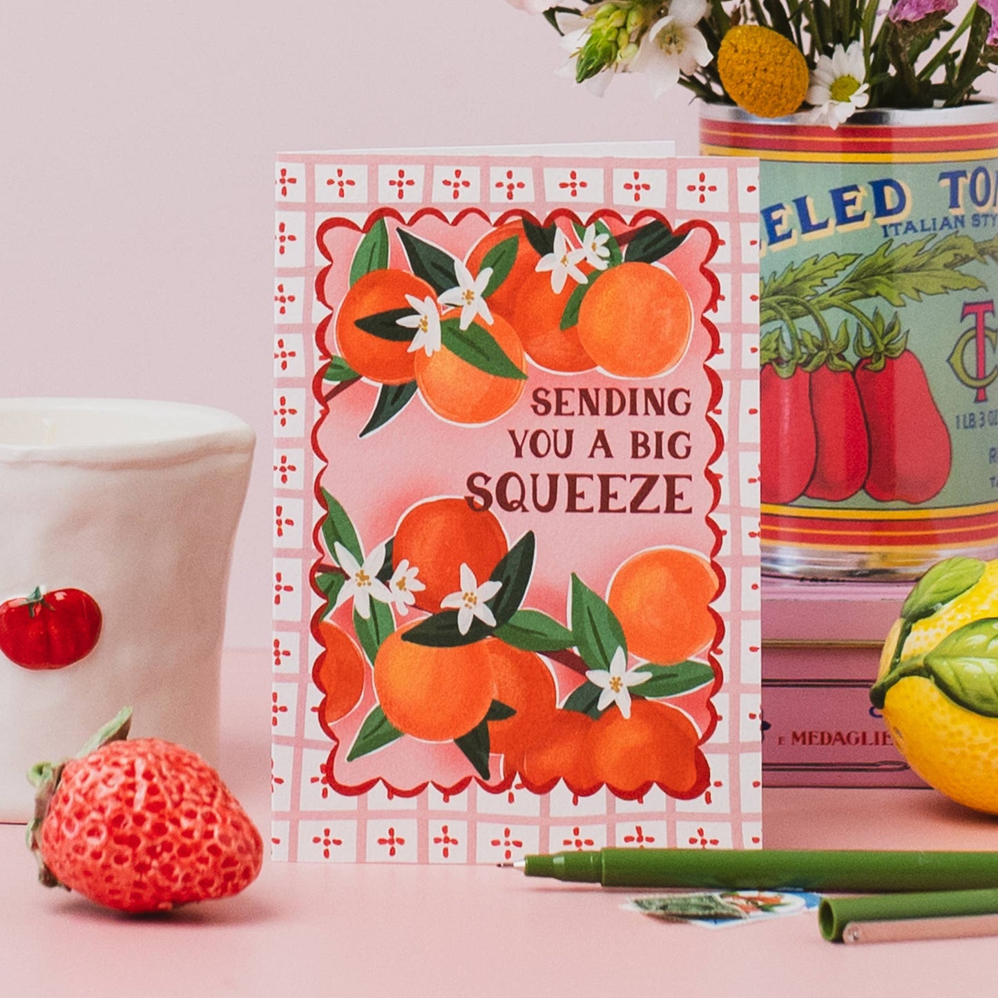 Close-up of 'Sending you a big squeeze' hand-lettered caption on orange greeting card