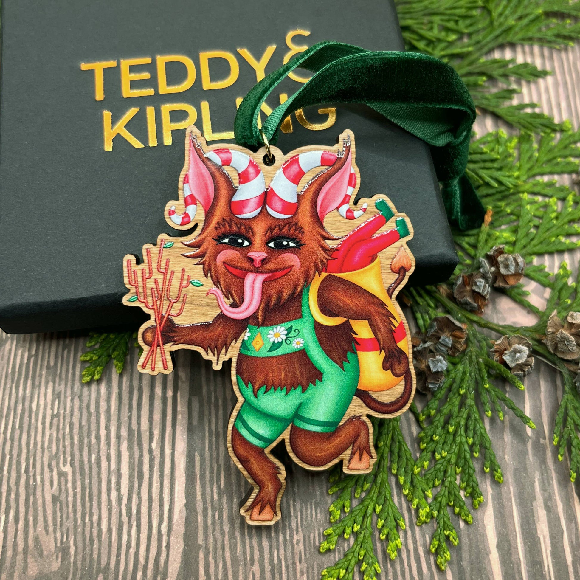 Krampus wooden Christmas tree decoration featuring Teddy & Kipling illustration, sustainably certified cherry wood, gold-plated ring, and dark green velvet ribbon