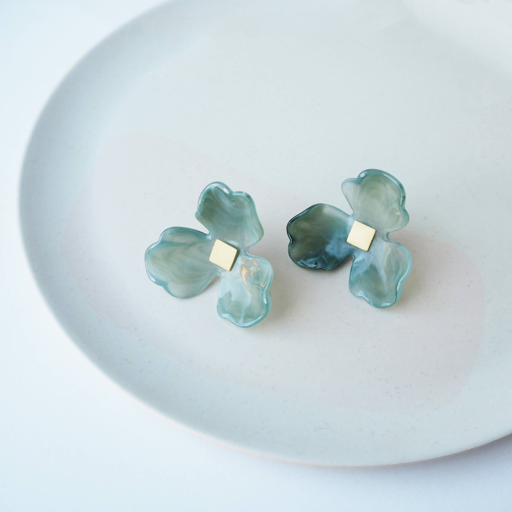 Close up of lightweight green acetate flower earrings with surgical steel posts